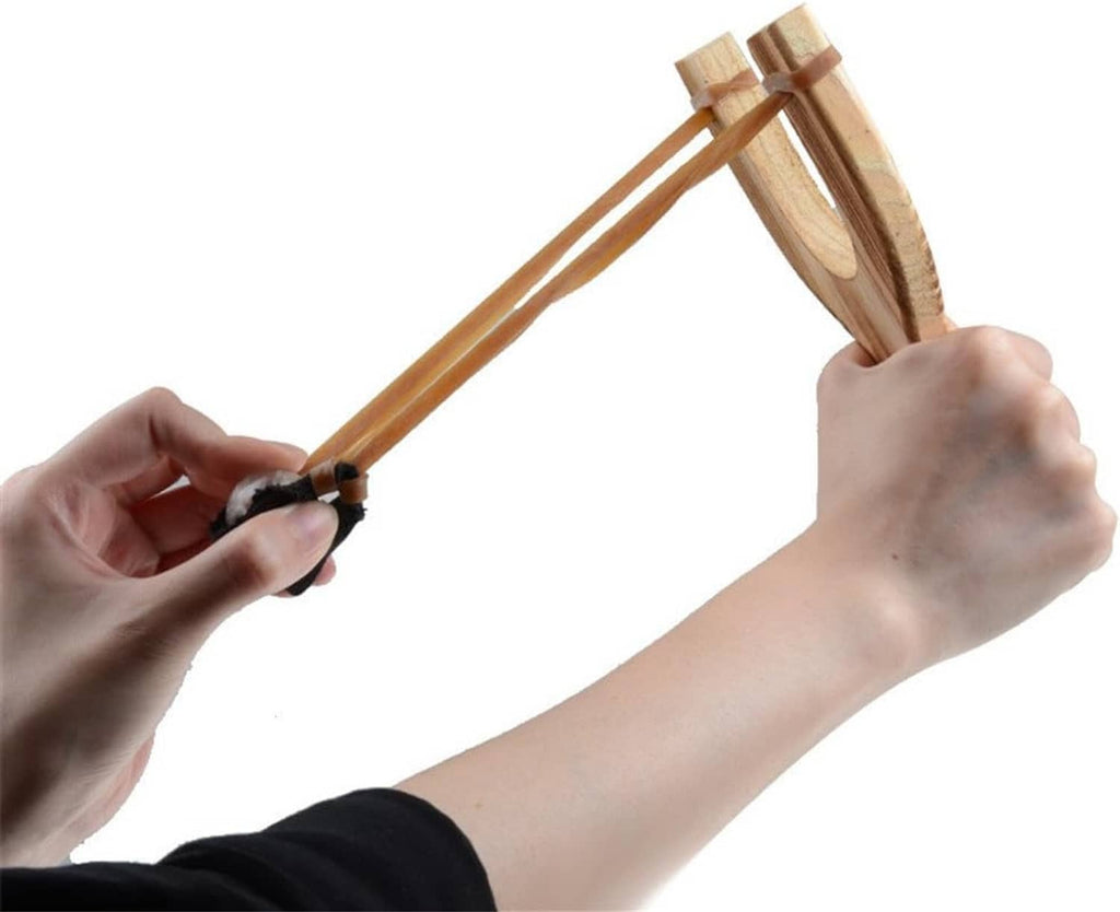 Hand holding a wooden slingshot with black band and tan elastic strap