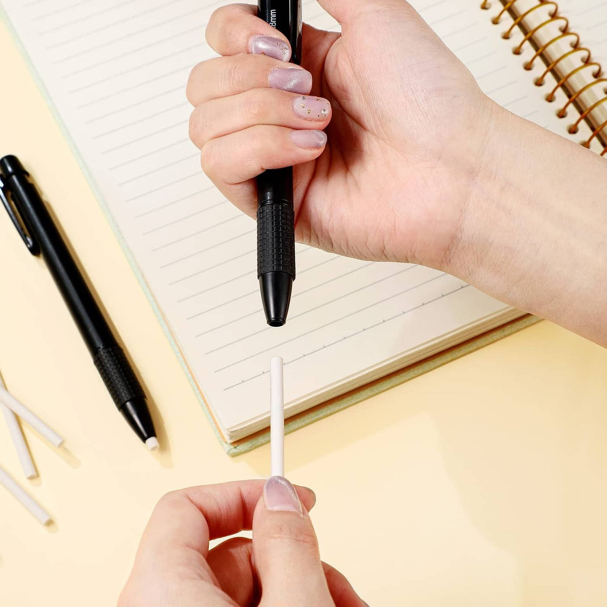 Black retractable eraser mechanical pen with eraser cap removed, held near paper