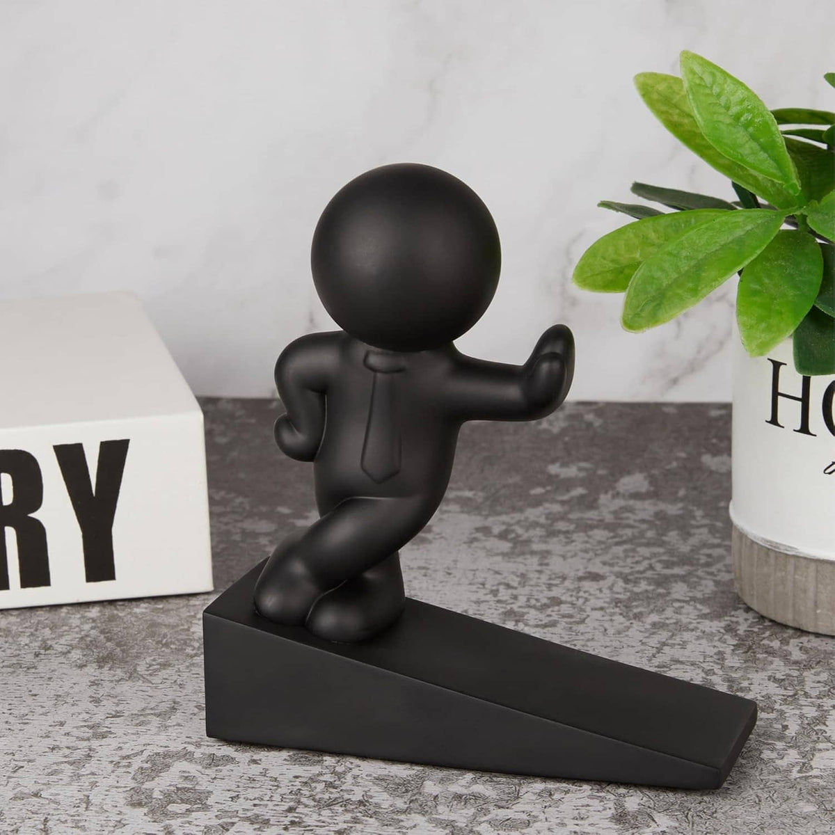 Black door stop figurine standing on a long flat base, decorative character design.