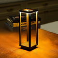 Black metal cordless lantern-style table lamp with warm LED glow, rectangular frame
