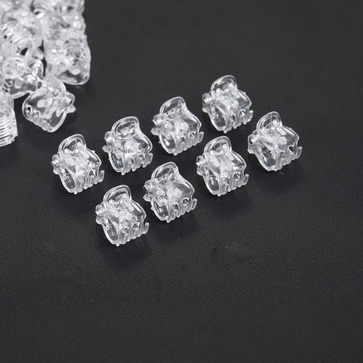 Clear mini claw hair clips scattered, close-up of transparent prongs
