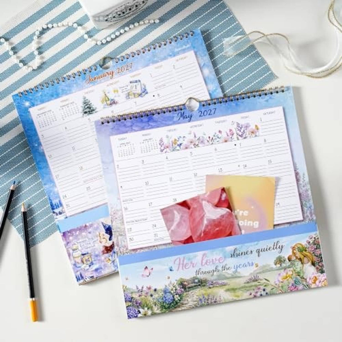 Two blue 2027 wall calendars shown side by side, each with a storage pocket and monthly grids