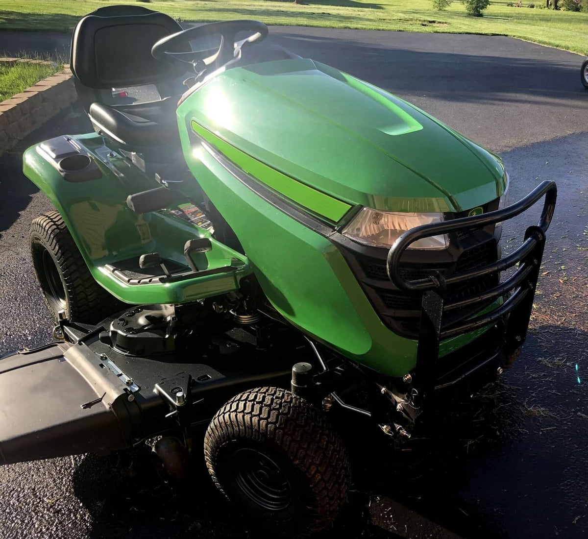 Black bumper brush guard on front of a green riding mower, angled view