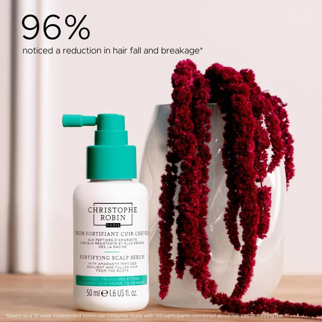 Fortifying scalp serum bottle with teal pump with red curls in the background
