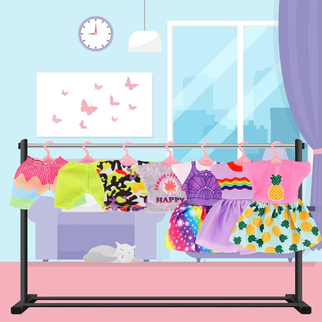 Assorted girl doll clothes hanging on a rack, with dresses and shorts sets