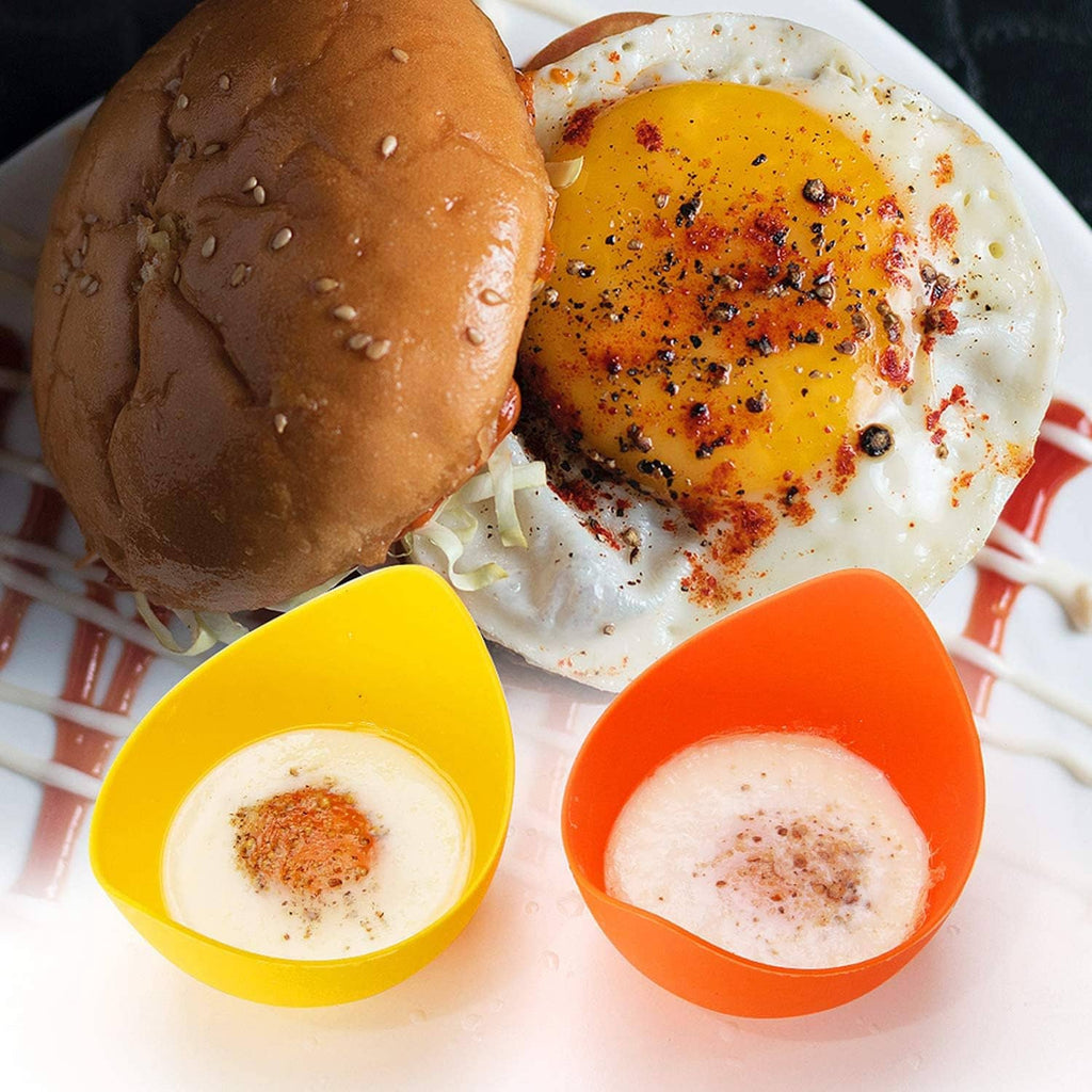 Colorful silicone egg poacher cups holding poached eggs on a plate