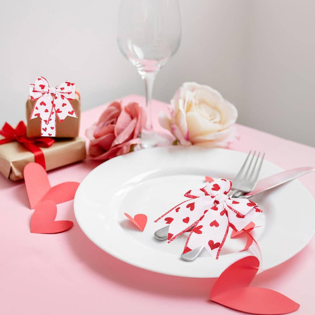 Red heart bow made from white wired ribbon on a plate with pink paper hearts