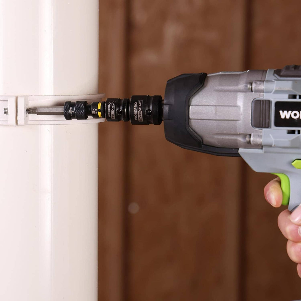 Impact wrench with black socket adapter driving a fastener, yellow ring visible.