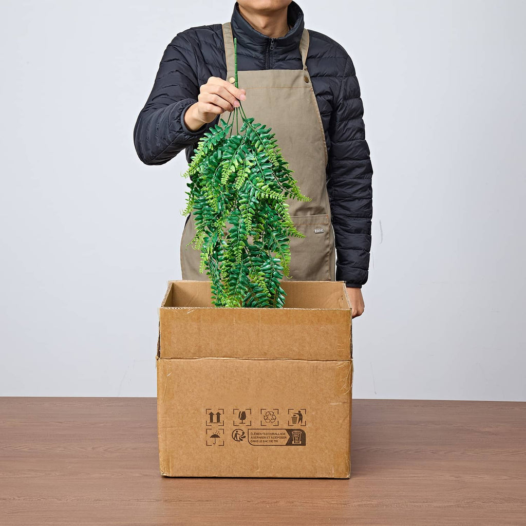 Artificial hanging Boston fern bush being unpacked from a cardboard box
