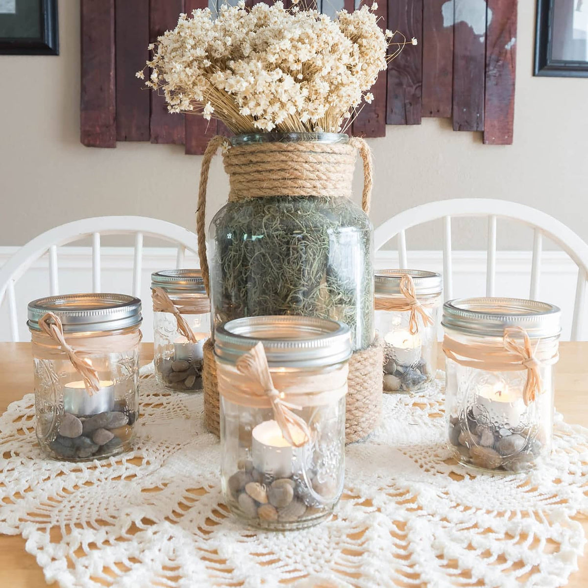 Unscented tea light candles burning inside glass jars on a lace table runner