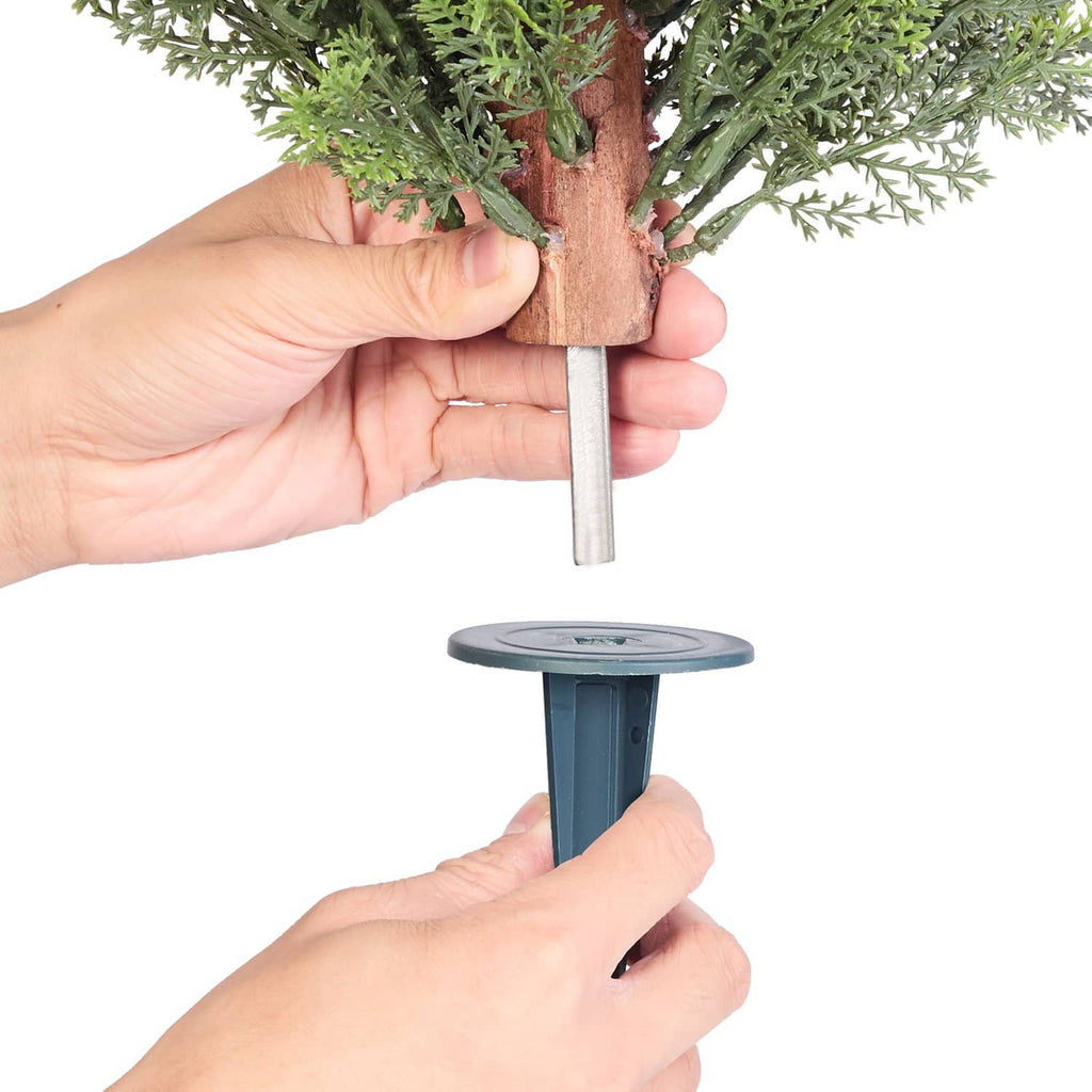 Artificial cypress topiary tree ground spike shown with hands securing the base