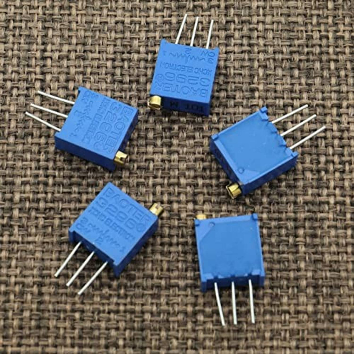 Loose blue multiturn trimmer potentiometers on fabric background with metal leads