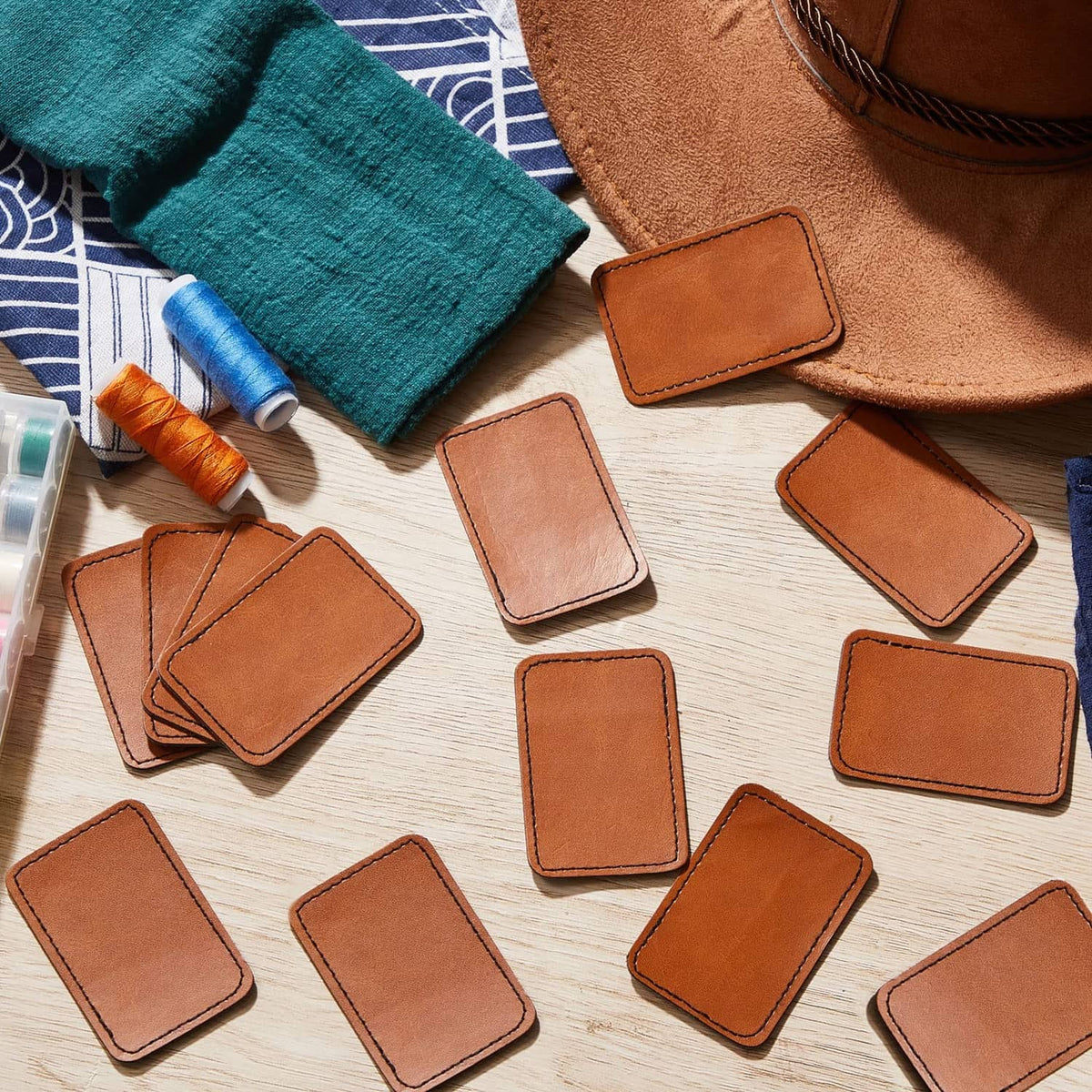 Tan blank leatherette hat patches, small rectangles with stitched edges, scattered