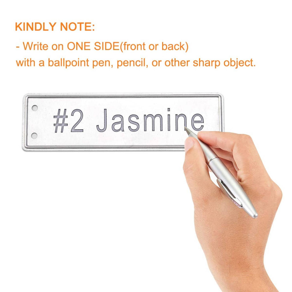 Aluminum plant tag being written on by hand, blank rectangular plate with hanging hole