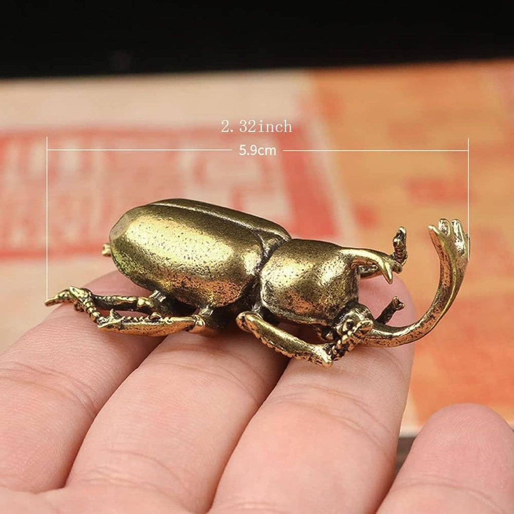 Miniature brass longhorn beetle figurine with curved antennae, on an open palm