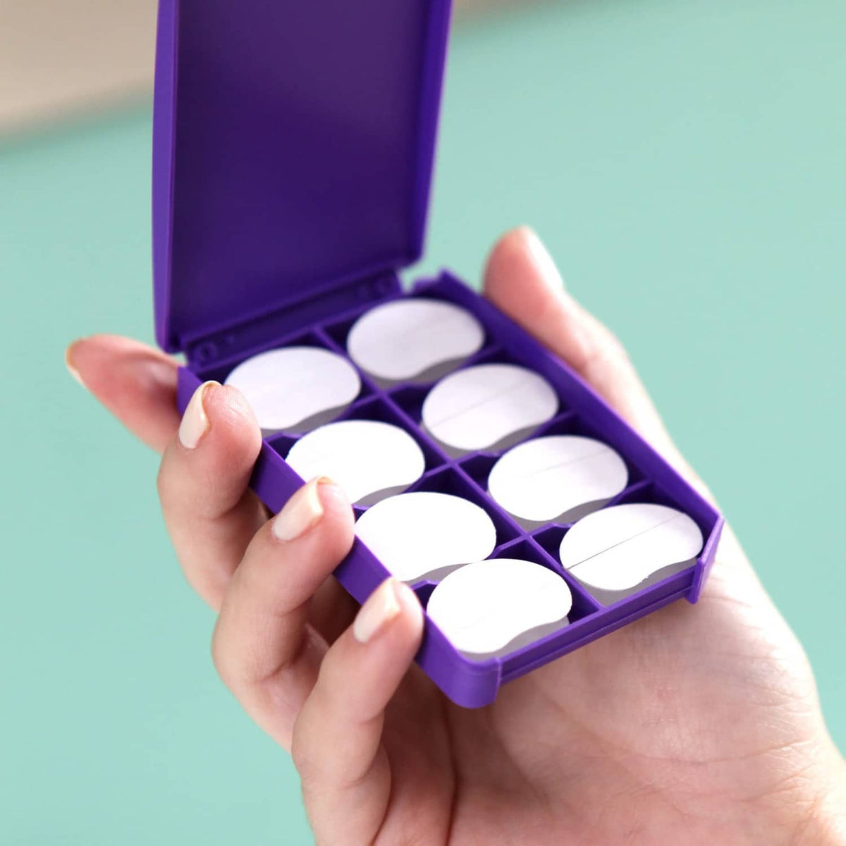 Purple case with clear, white round ear-correction adhesive pads