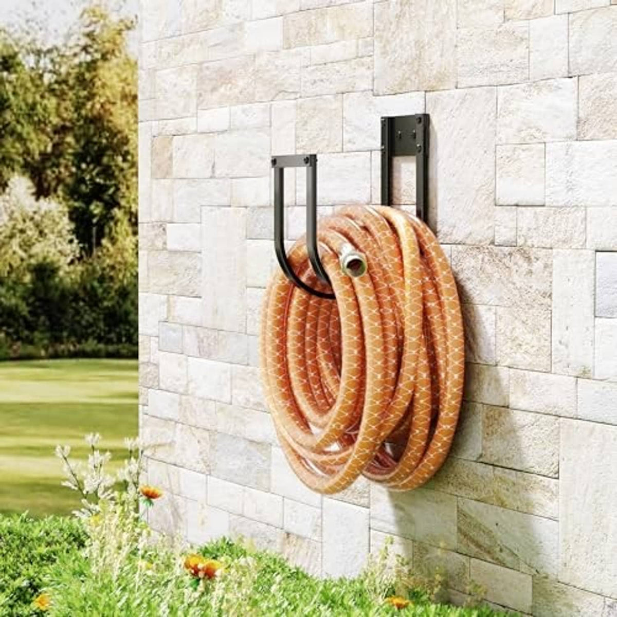 Black metal wall-mounted hose hanger holding coiled orange striped hose on stone wall