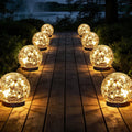 Set of 8 warm-white solar glass globe lights with glowing spheres on a deck