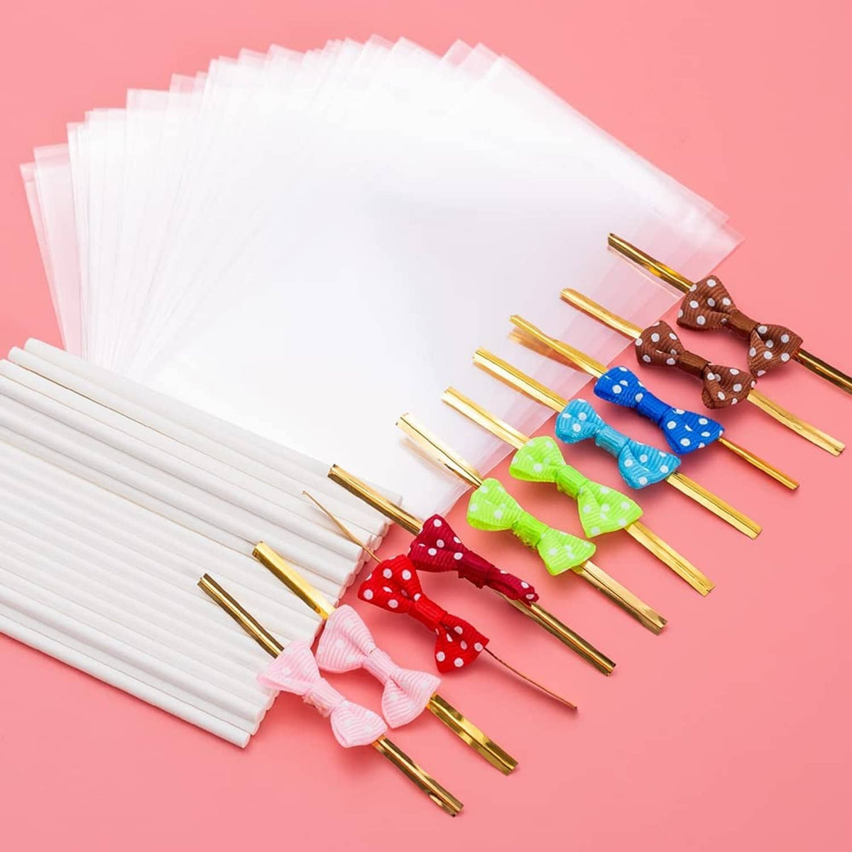 White wrappers stacked with gold-tipped cake pop sticks and bow-decorated candy pops