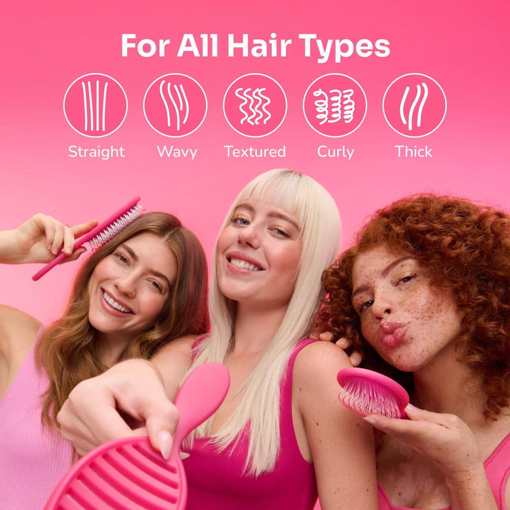 Mini detangling hair brush held in hand, pink paddle brush with short bristles