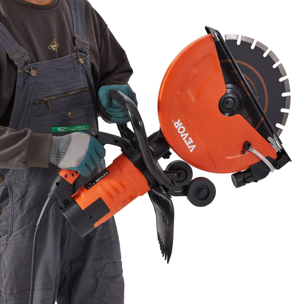 Electric concrete saw held in gloves during cutting, orange blade and wheeled base