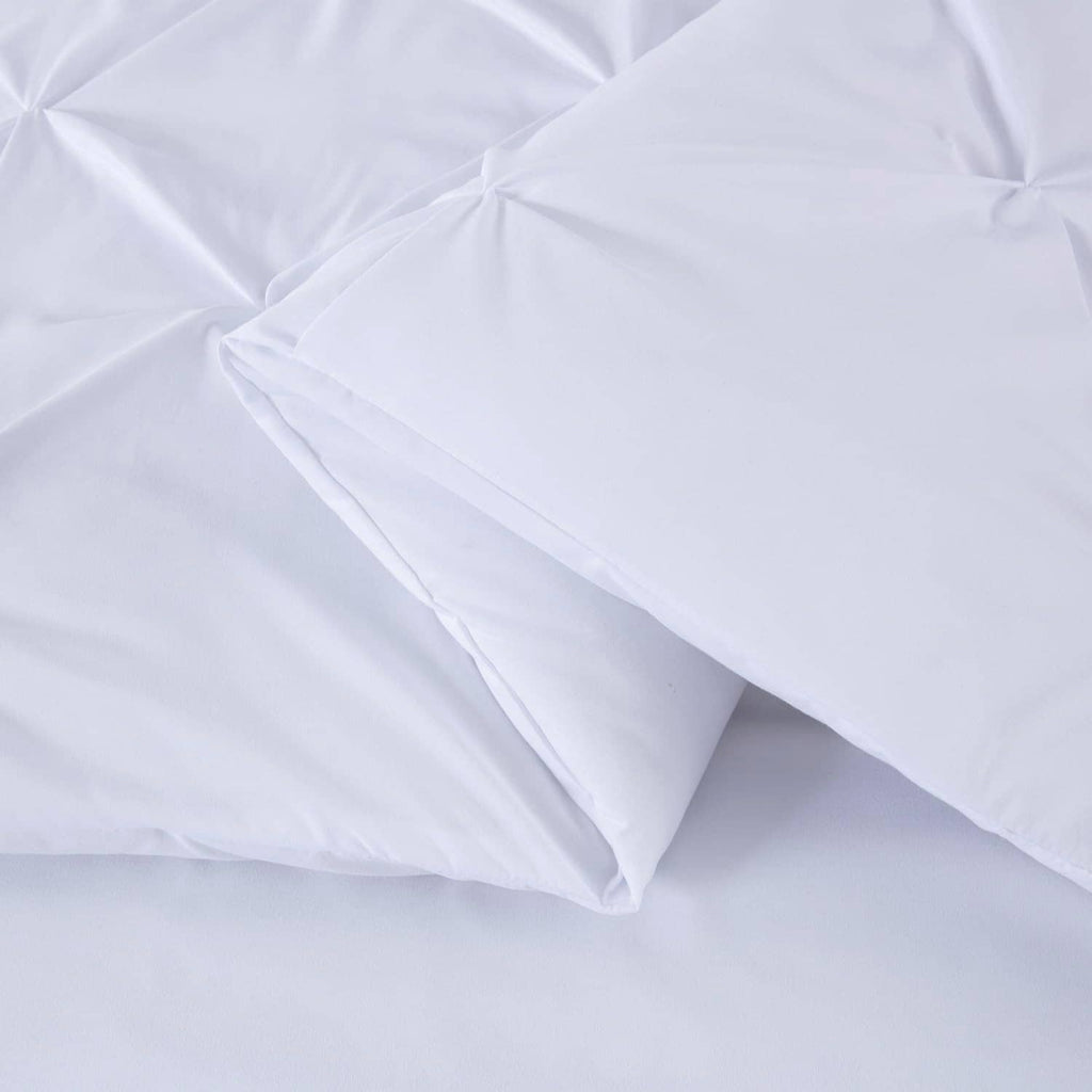 White comforter with diamond pinch pleat quilting and a folded corner edge