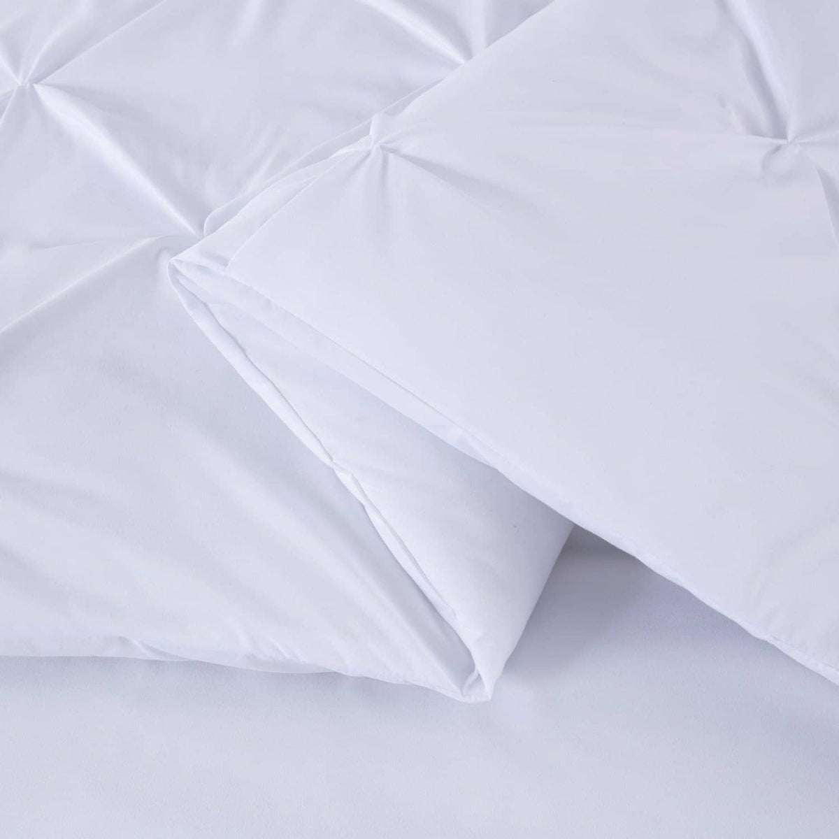 White comforter with diamond pinch pleat quilting and a folded corner edge