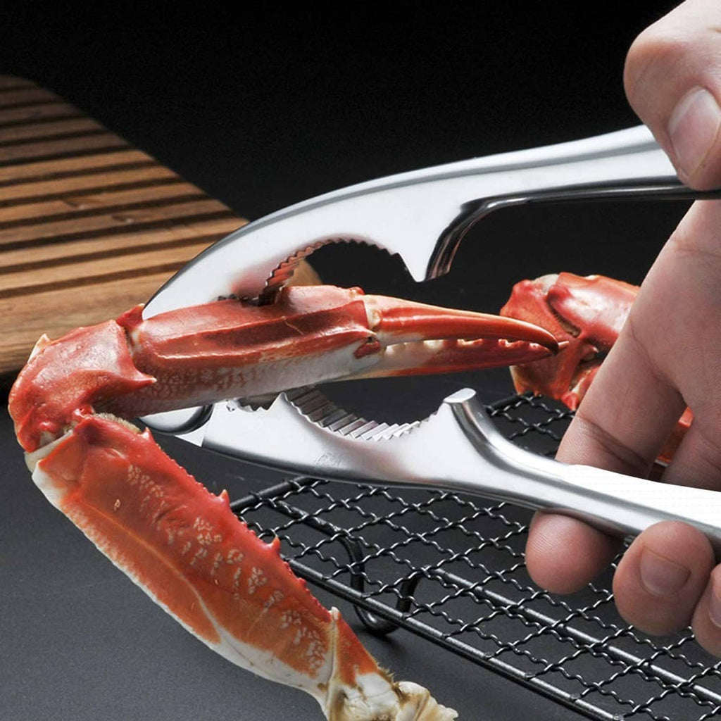 Metal seafood cracker cracking crab claw, ribbed jaws held by a hand