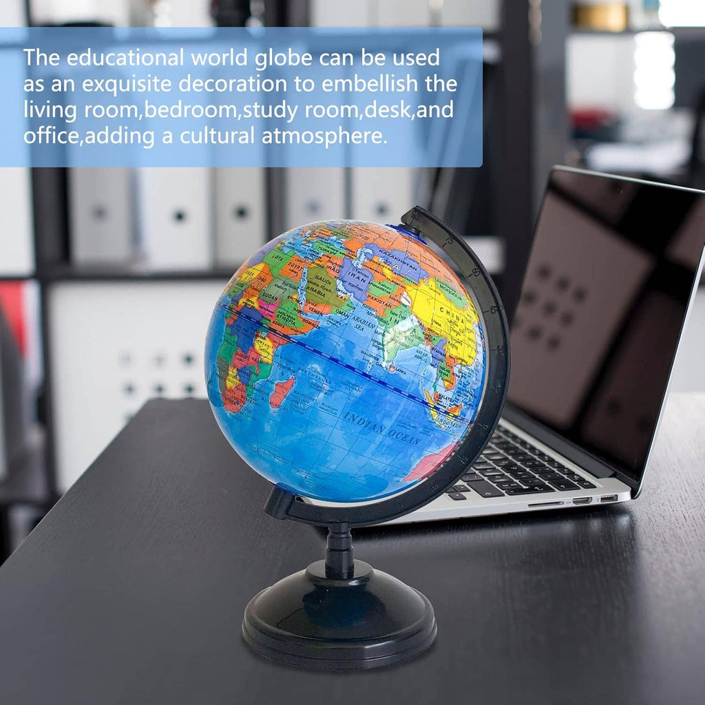 World globe on black stand sitting beside a laptop