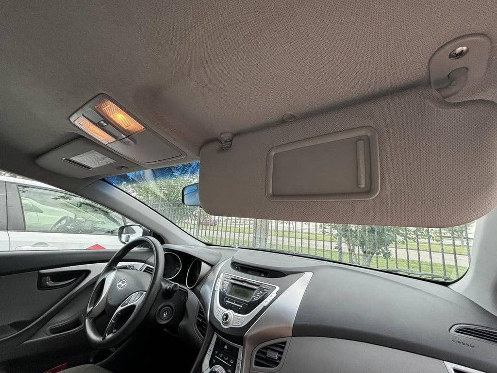 Grey left sun visor installed in car interior above the dashboard