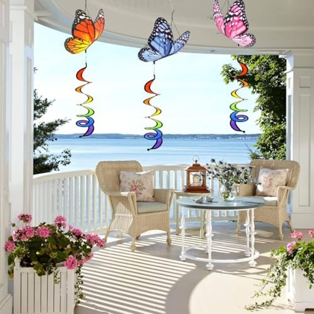 Three hanging butterfly wind spinners with rainbow curlie springs over a patio