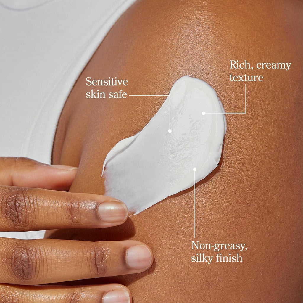 Hand holding a spoonful of white whipped body cream applied to bare skin