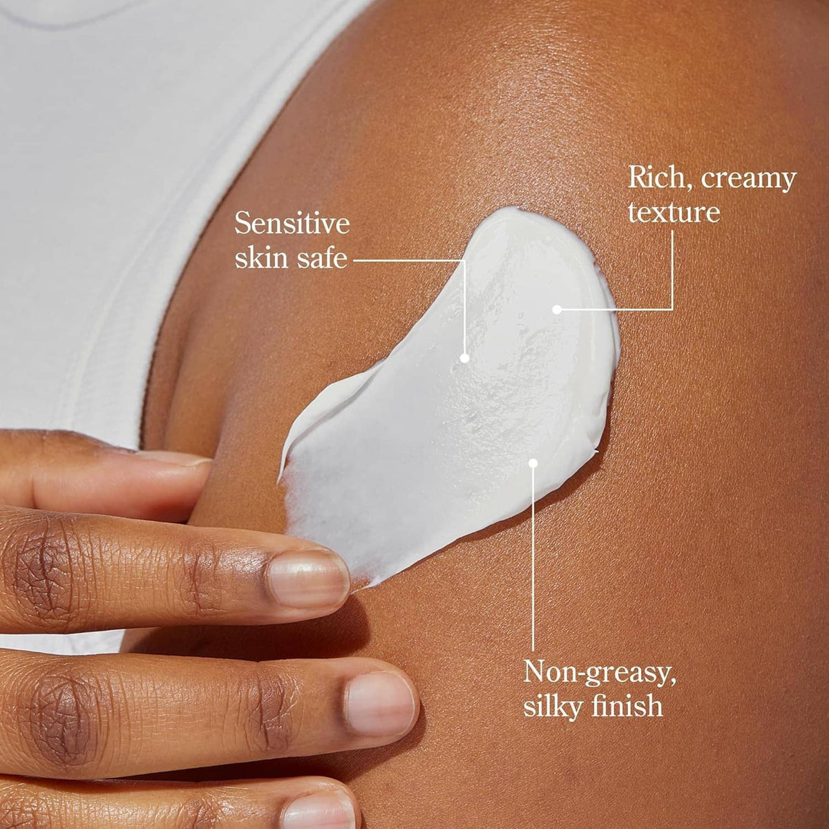 Hand holding a spoonful of white whipped body cream applied to bare skin