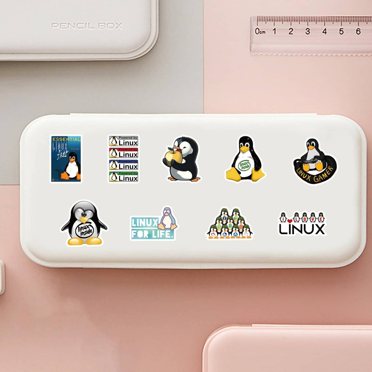 Linux stickers on a white pencil case, showing multiple penguin icons and logos