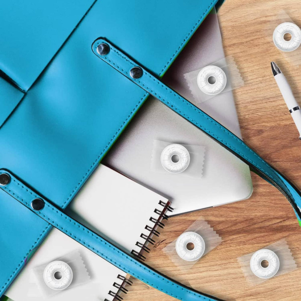 White round Pep O Mint mints scattered around teal folders and wooden desk