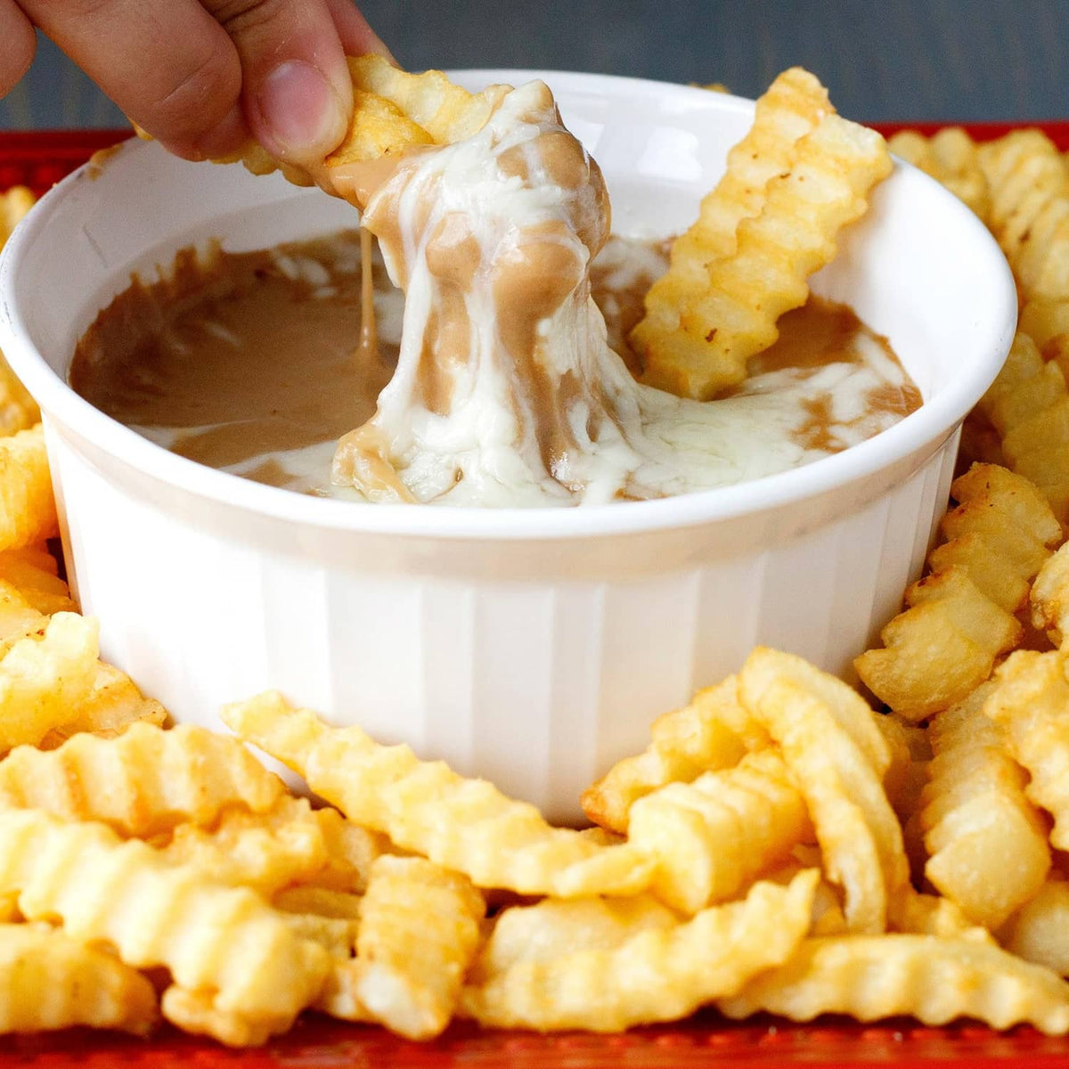 Brown gravy being poured into a cup with biscuit pieces