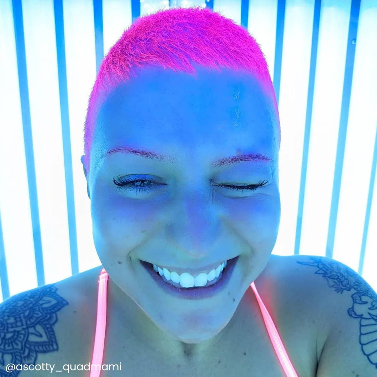 Short pixie hairstyle with vibrant purple-to-blue dyed hair and closed-eye smile