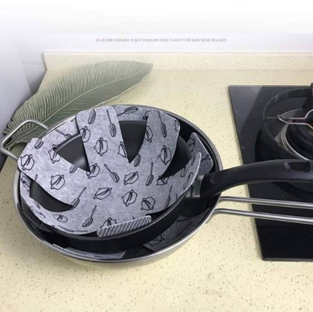 Gray utensil-pattern pot protector pad covering a pan surface, preventing contact