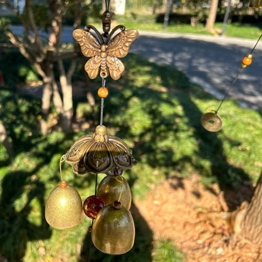 Bronze-toned butterfly wind chime with four bells hanging from a garden hook