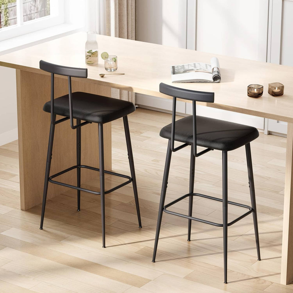 Black bar stools with padded seats, curved footrests, and sturdy metal legs