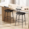 Black bar stools with padded seats, curved footrests, and sturdy metal legs