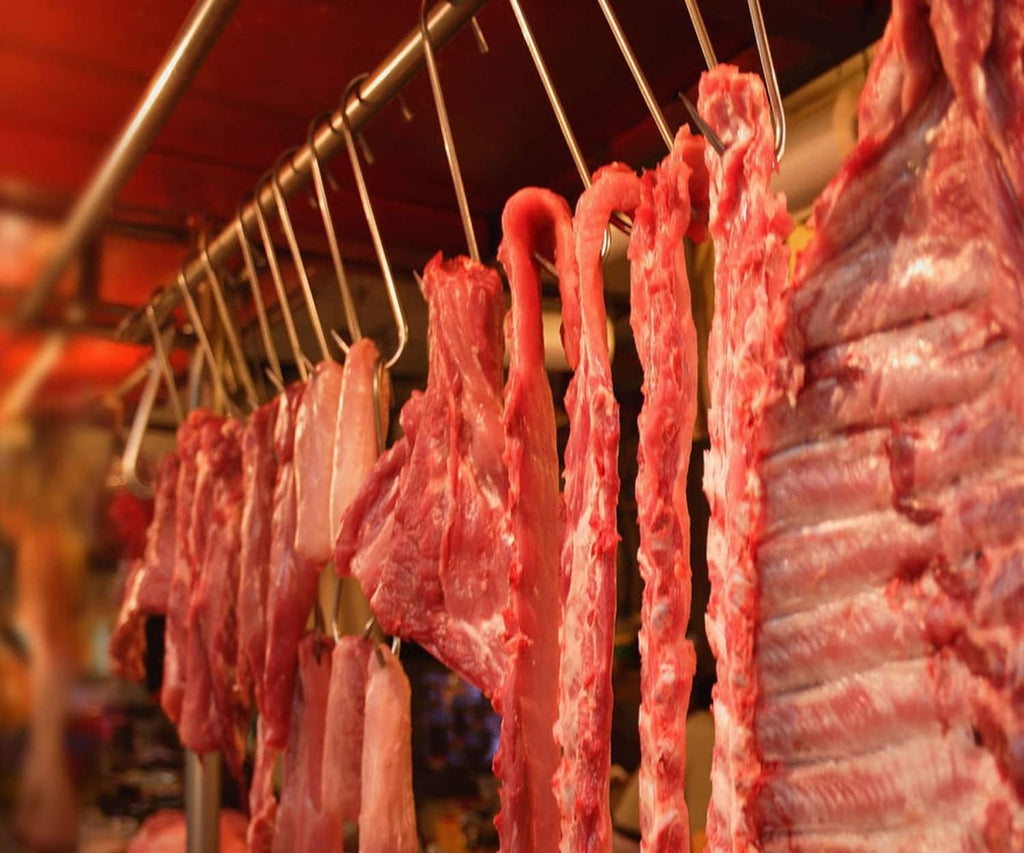 Stainless steel S-hooks holding cured meat pieces for processing