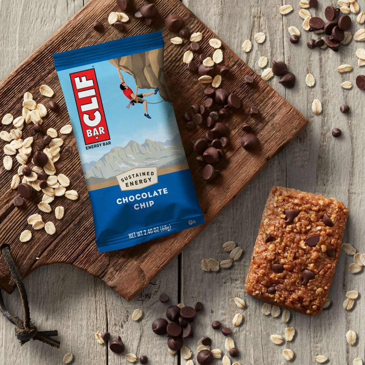 Chocolate chip energy bar pack and bar on wooden board with oats and chips