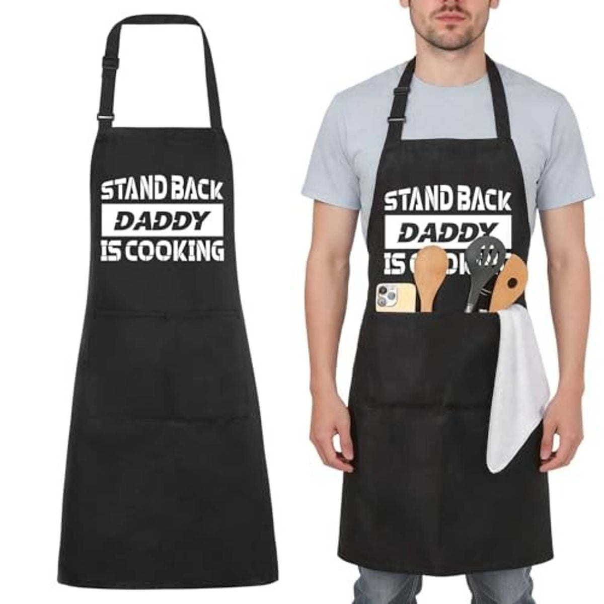 Black apron worn over a light shirt, front pocket, “STAND BACK DADDY IS COOKING” print