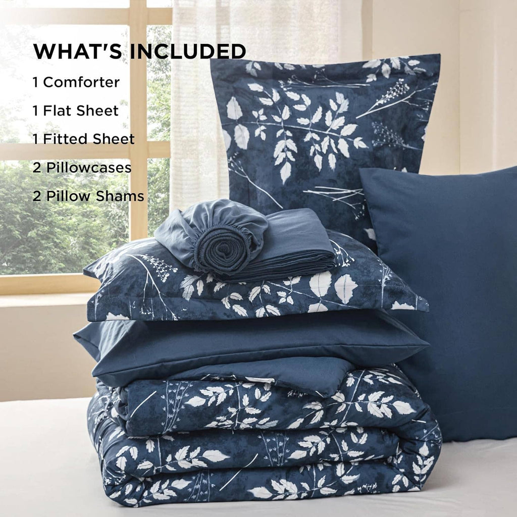 Folded navy floral comforter set with solid blue sheets and pillow shams