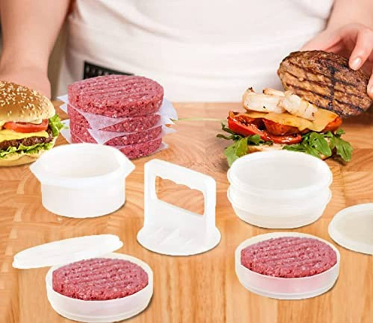 White freezer containers and patty molds with raw burger patties on wooden table
