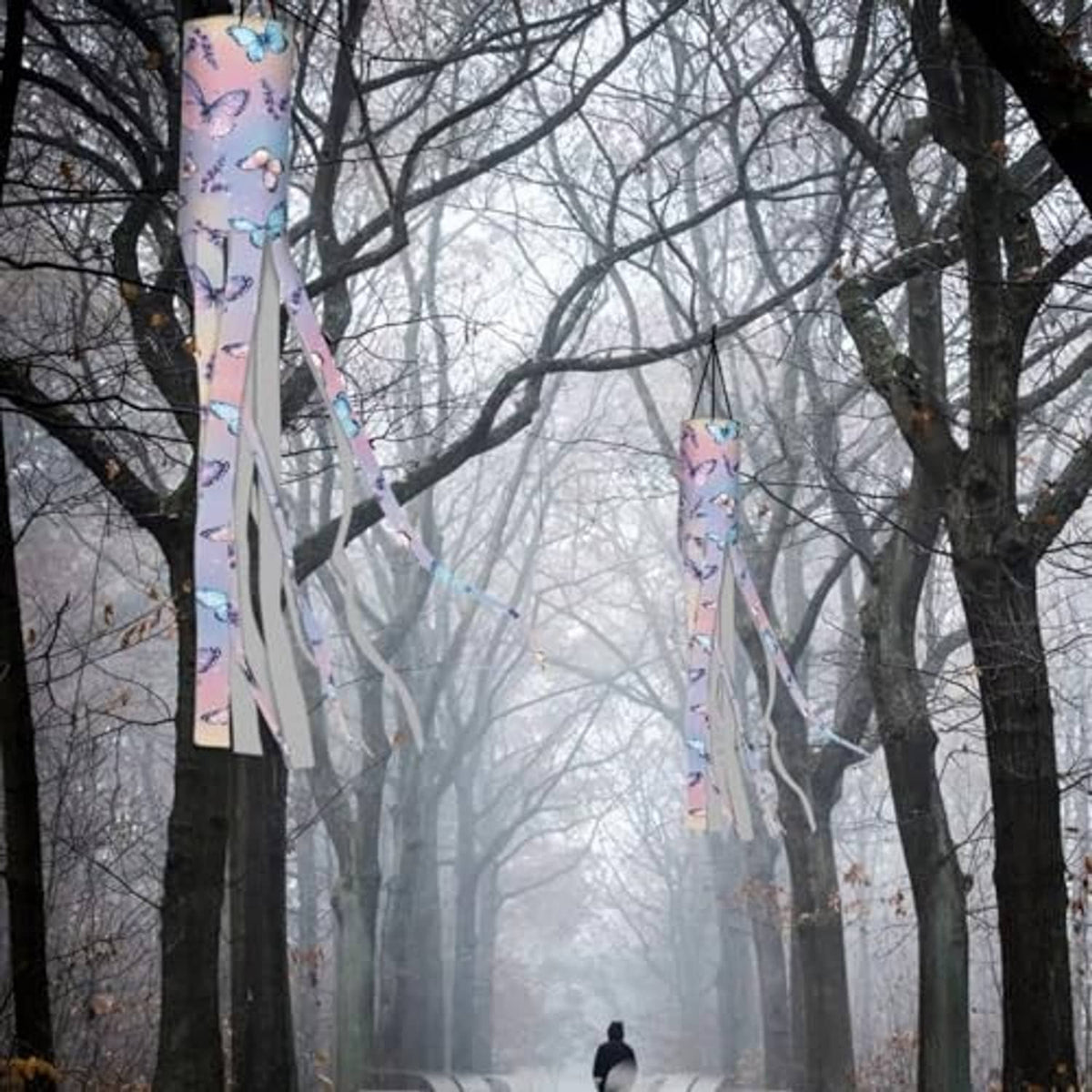 Two butterfly print windsock flags with long ribbon tails, hanging in trees