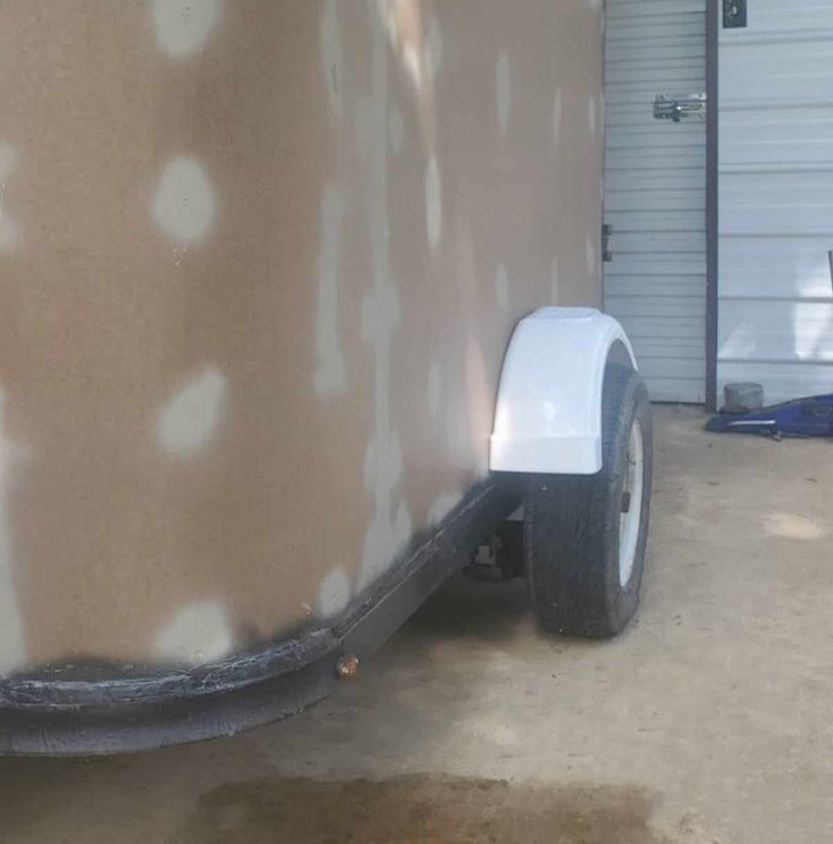 White trailer fender installed beside wheel on a trailer