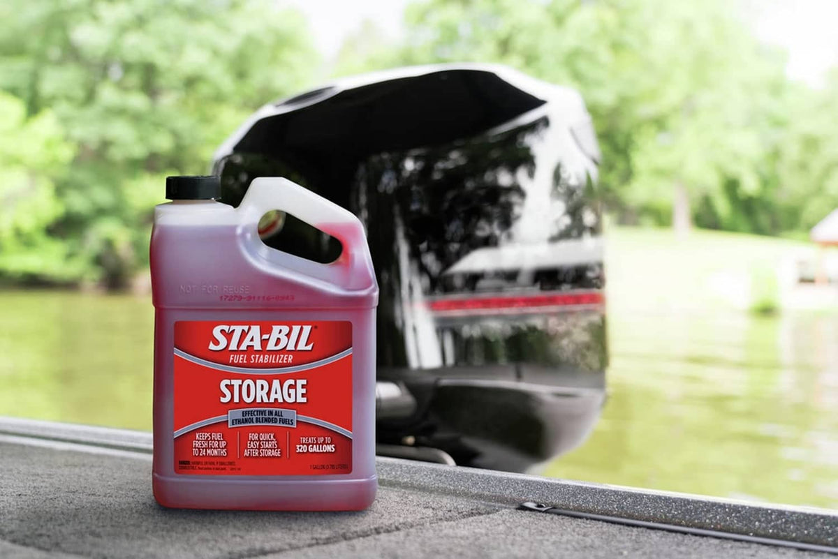 Red fuel stabilizer jug with white spout on road beside parked car