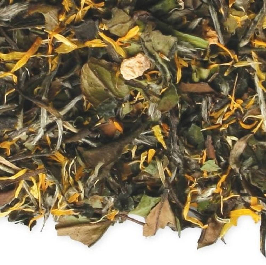 Close-up of loose leaf tea with green leaves, brown fragments, and orange peel